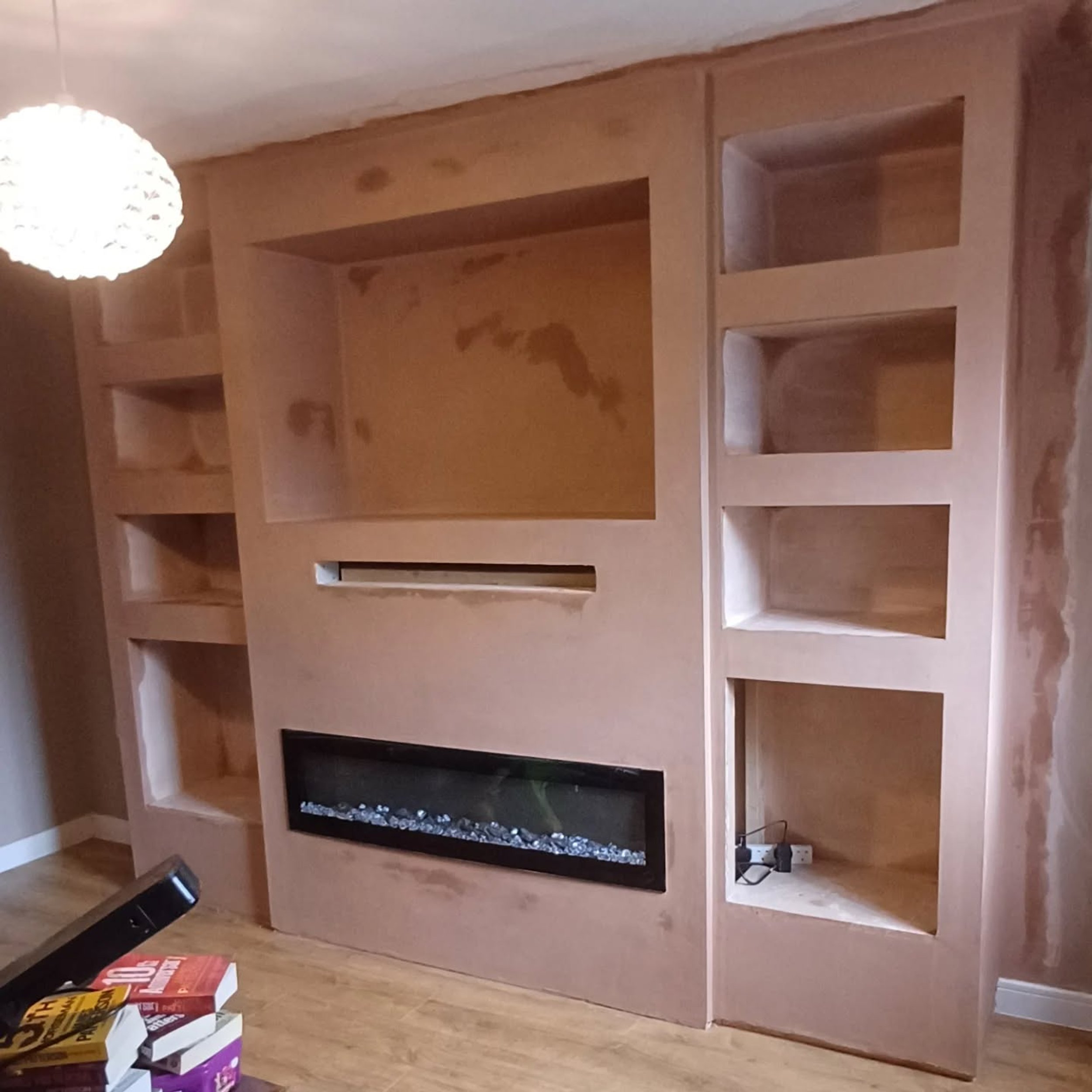 Media wall with fireplace and shelving niches after plastering